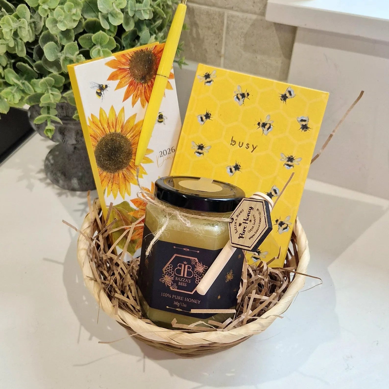 Gift basket with honey jar, sunflower-themed cards, and bee decorations on a light surface.